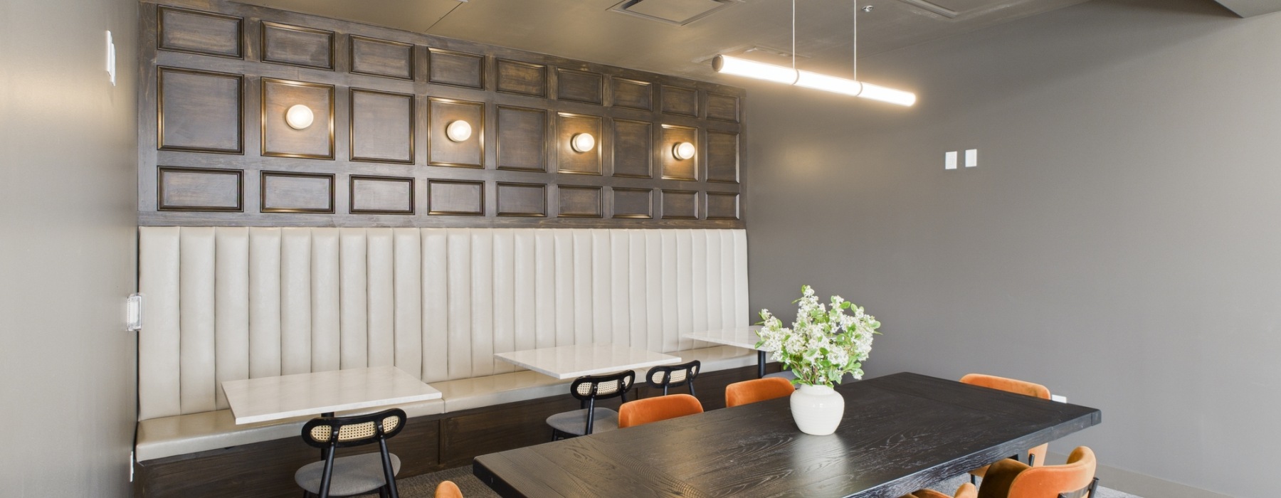 Lounge with orange chairs and black tables