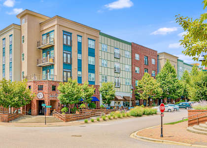 A multi-story building with a red brick entrance and a clock on the wall. at The Lofts at Reynolds Village Apartments, Asheville