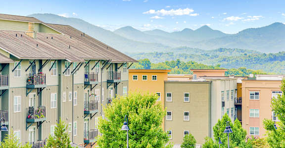 Apartment buildings with balconies overlooking a mountain range. at The Lofts at Reynolds Village Apartments, Asheville