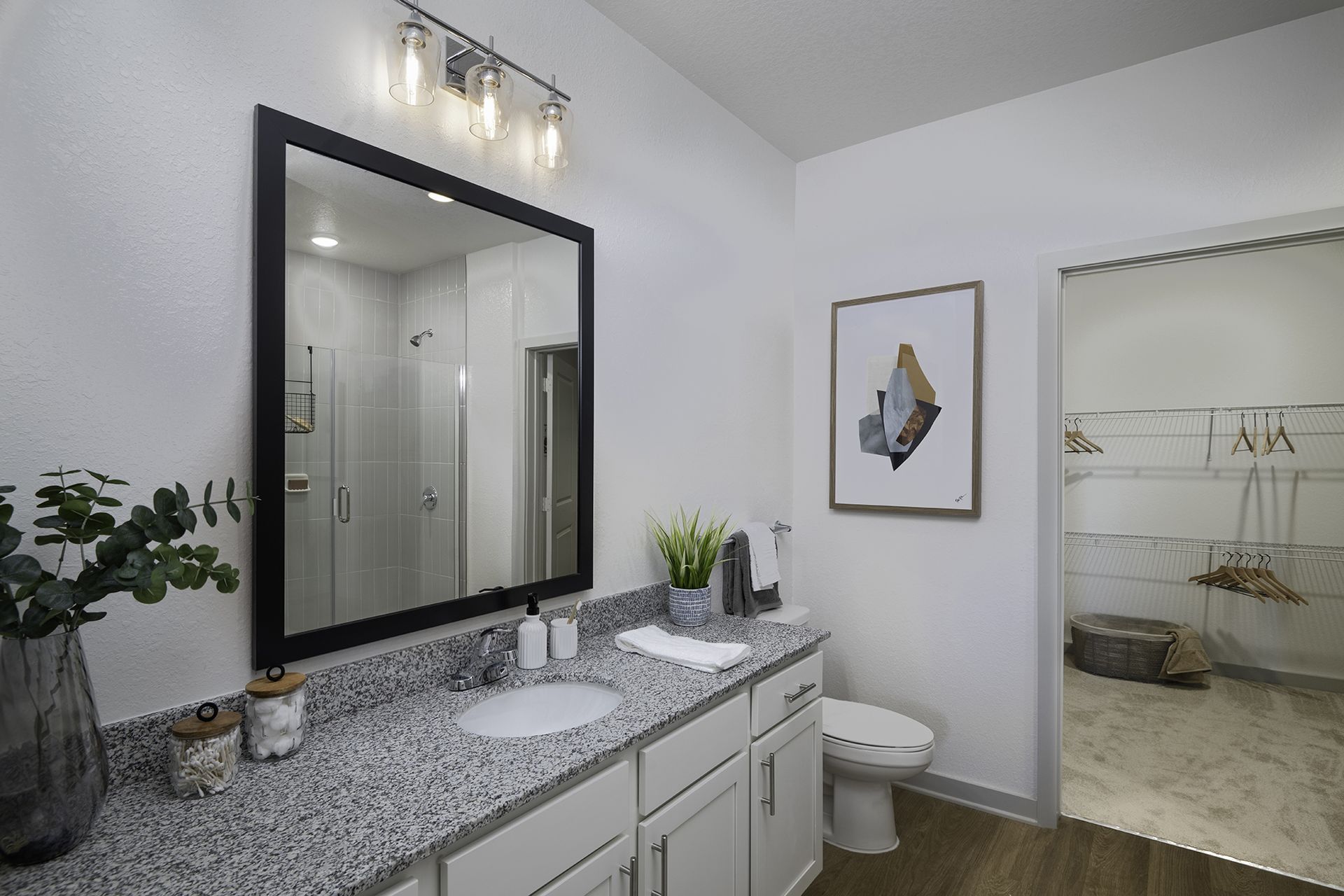 Modern bathroom with granite vanity, wall mirror, white cabinets, and a toilet beside a shower area at Livano Wildwood.