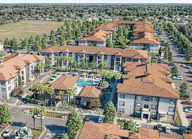 A large, well-maintained apartment complex with a pool and landscaping at Maison at Solivita Marketplace Apartment Homes, Kissimmee, 34758