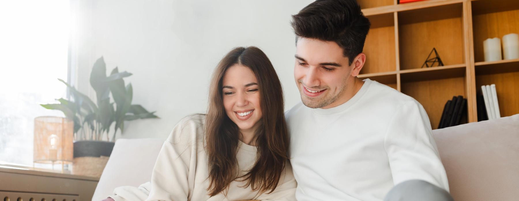 a man and woman sitting on a couch with a dog