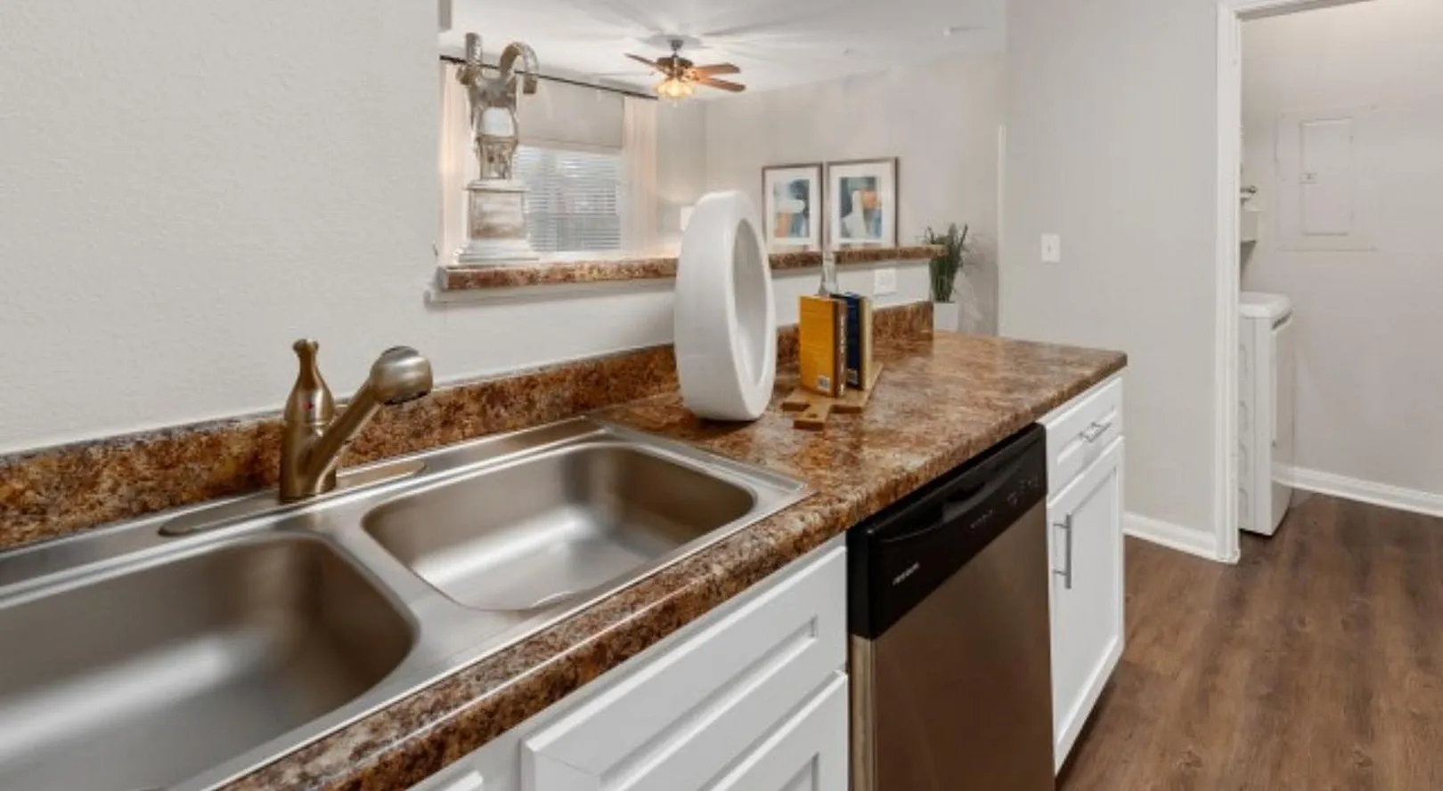 Charming kitchen with elegant granite countertops, a modern dual sink, and sleek stainless steel appliances, all set against warm wood flooring.