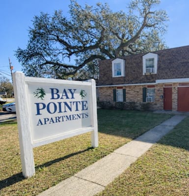 A sign for Bay Pointe Apartments stands in front of a brick building.