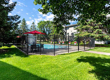 a fenced in pool with a table and umbrella in a yard