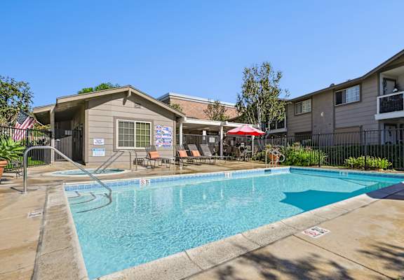 Community pool area with lounge chairs and mature landscaping at Sunnyside Senior Apartments in San Dimas, CA