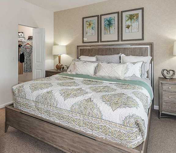 A bedroom with a large bed and a nightstand with a lamp.