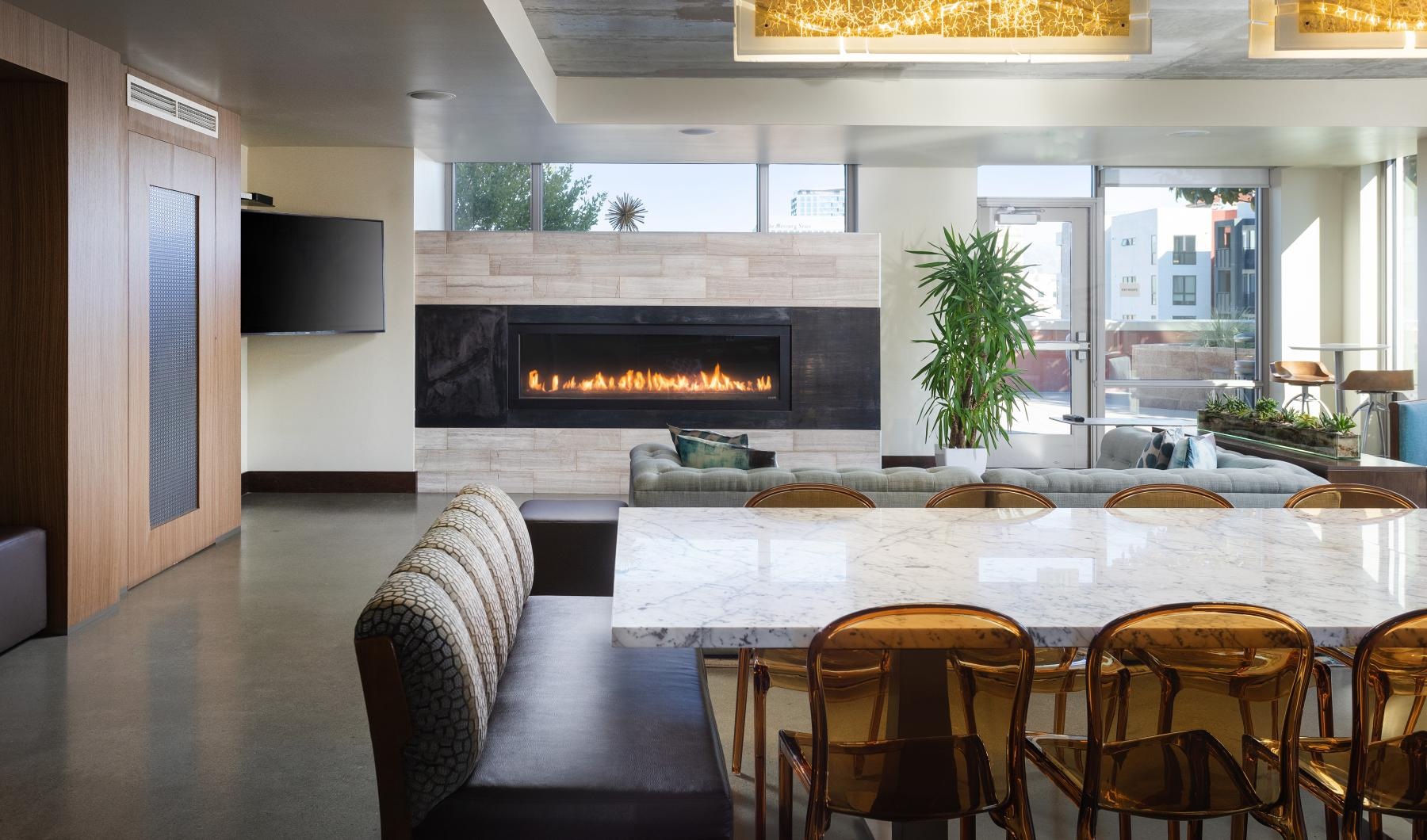a clubroom with a table, chairs and a fireplace