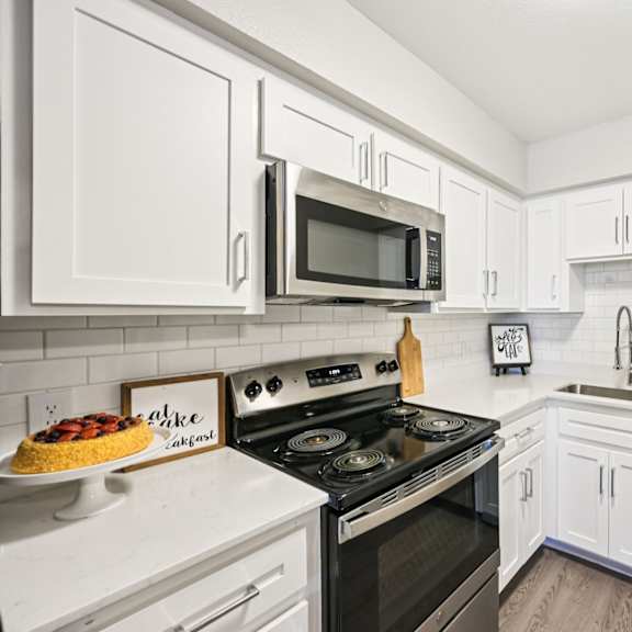 a kitchen with white cabinets and black appliances