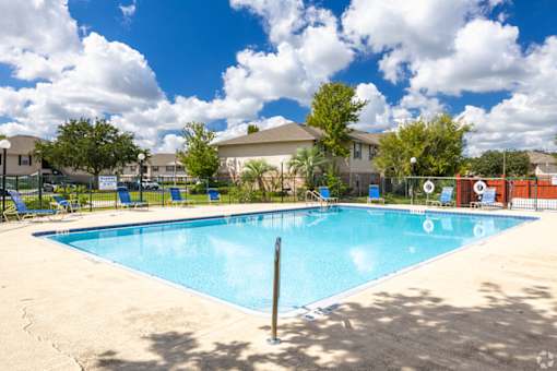 A large swimming pool surrounded by a fence and trees.