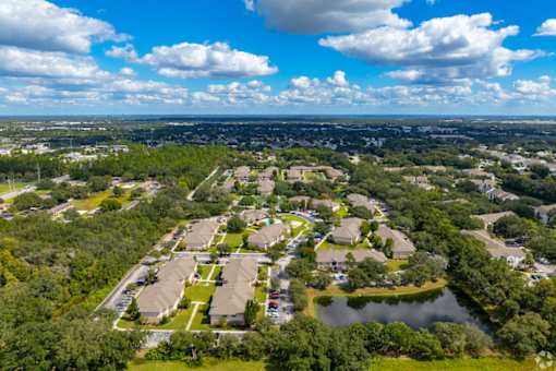A bird's eye view of a residential area with houses, trees, and a lake.