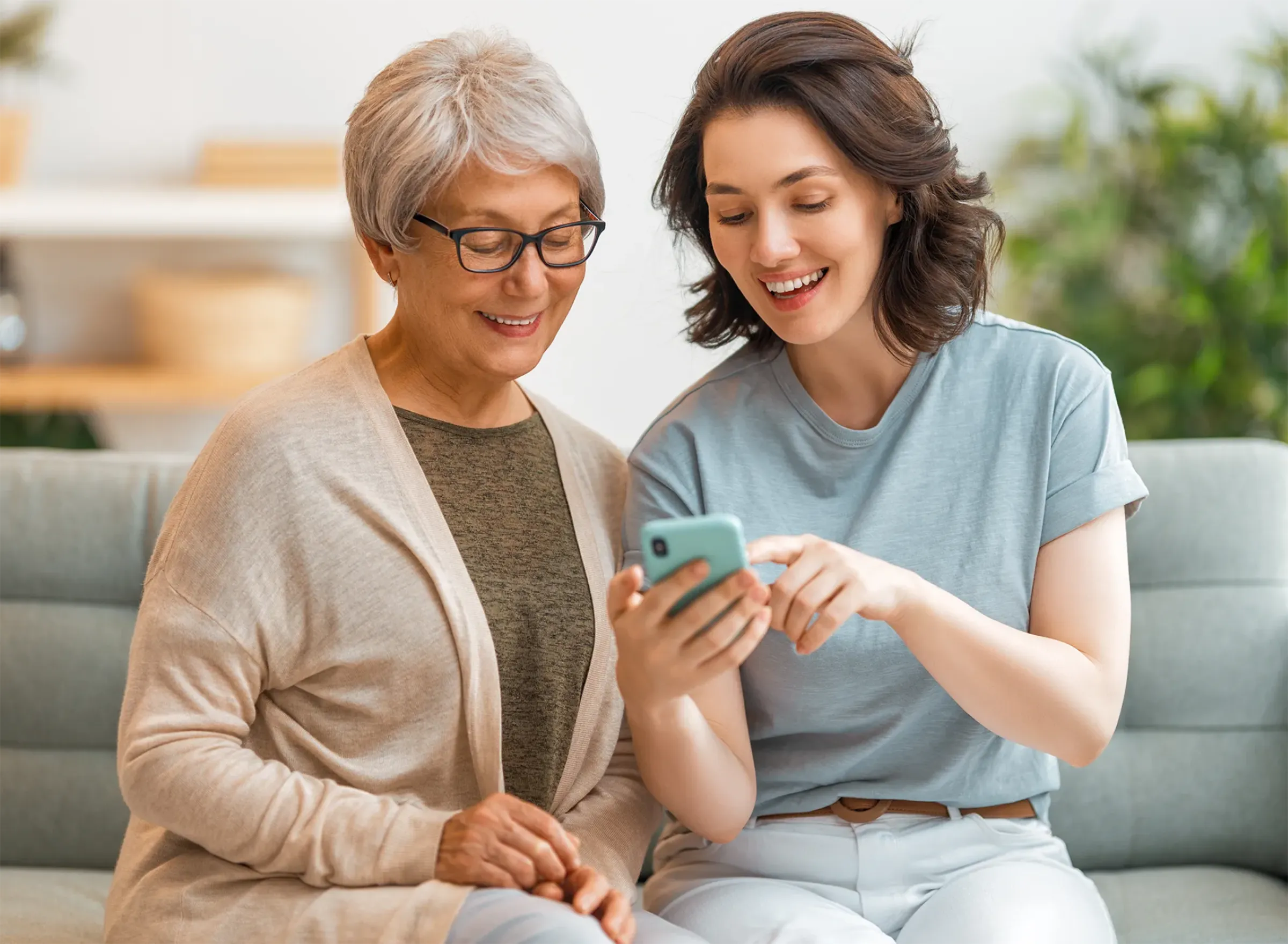 senior woman with young woman on a couch looking at phone