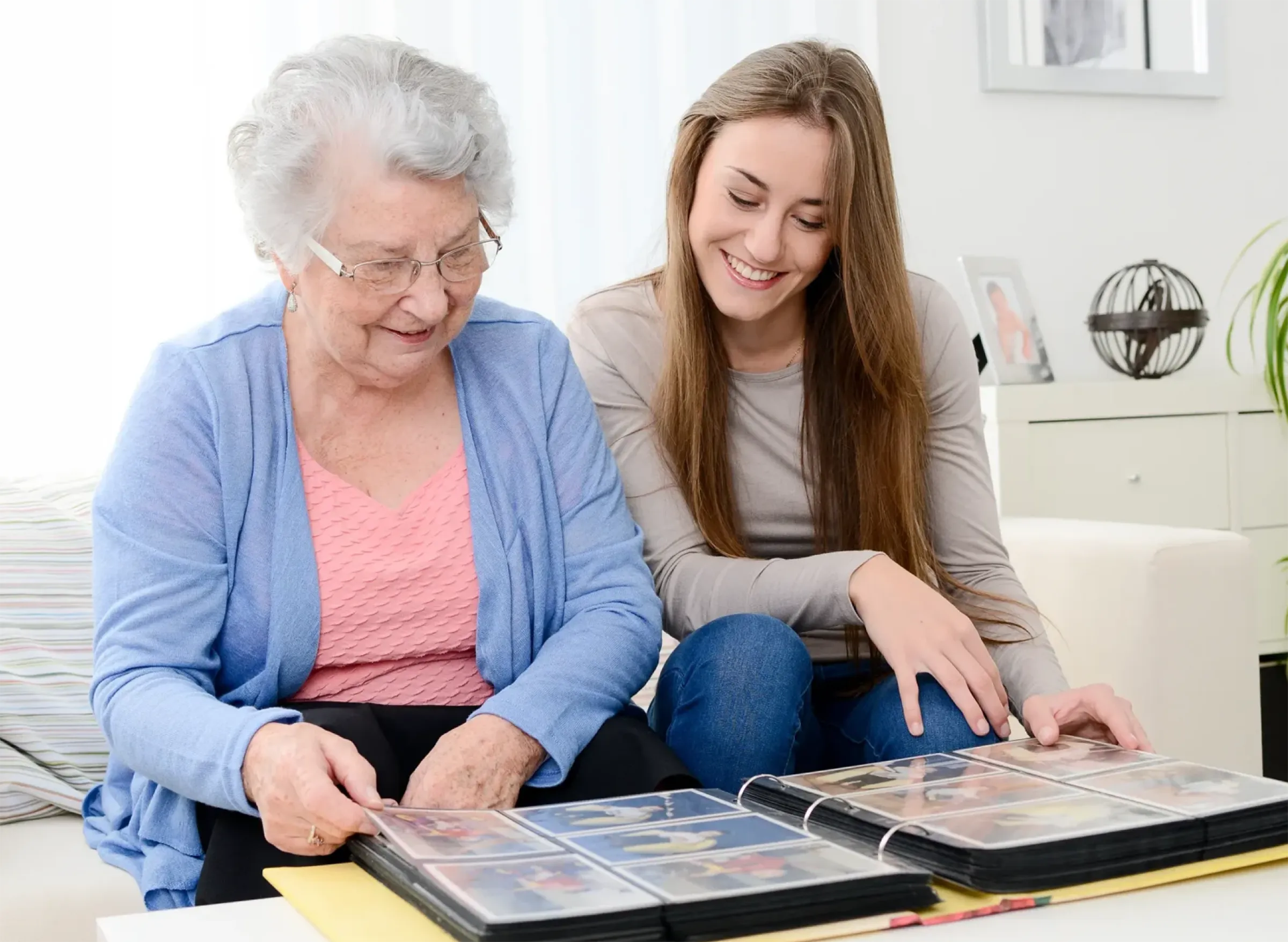 senior woman and young woman on couch looking at photo album