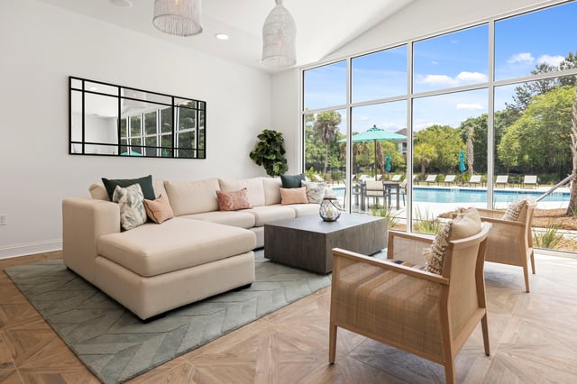 Lounge area with sectional sofa and chairs overlooking a swimming pool.