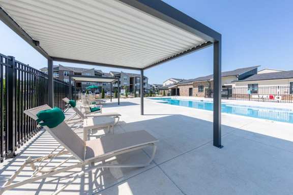 A pool area with a white canopy and lounge chairs.