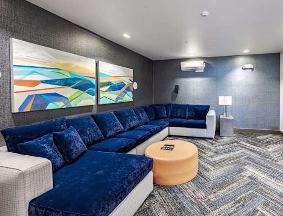 A modern living room with a blue velvet sofa and a television. at Kirkland Crossing Apartments, Kirkland, WA
