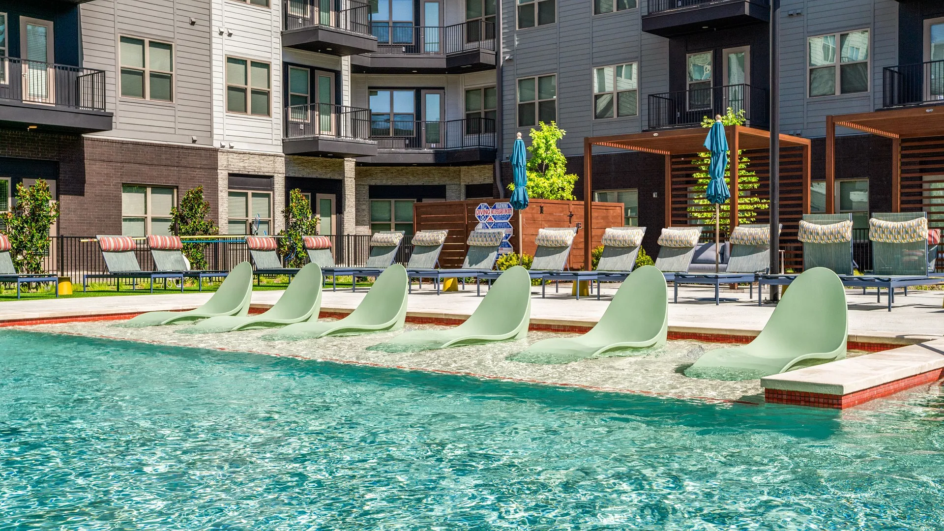 Chairs in a pool area with modern apartments in the background.