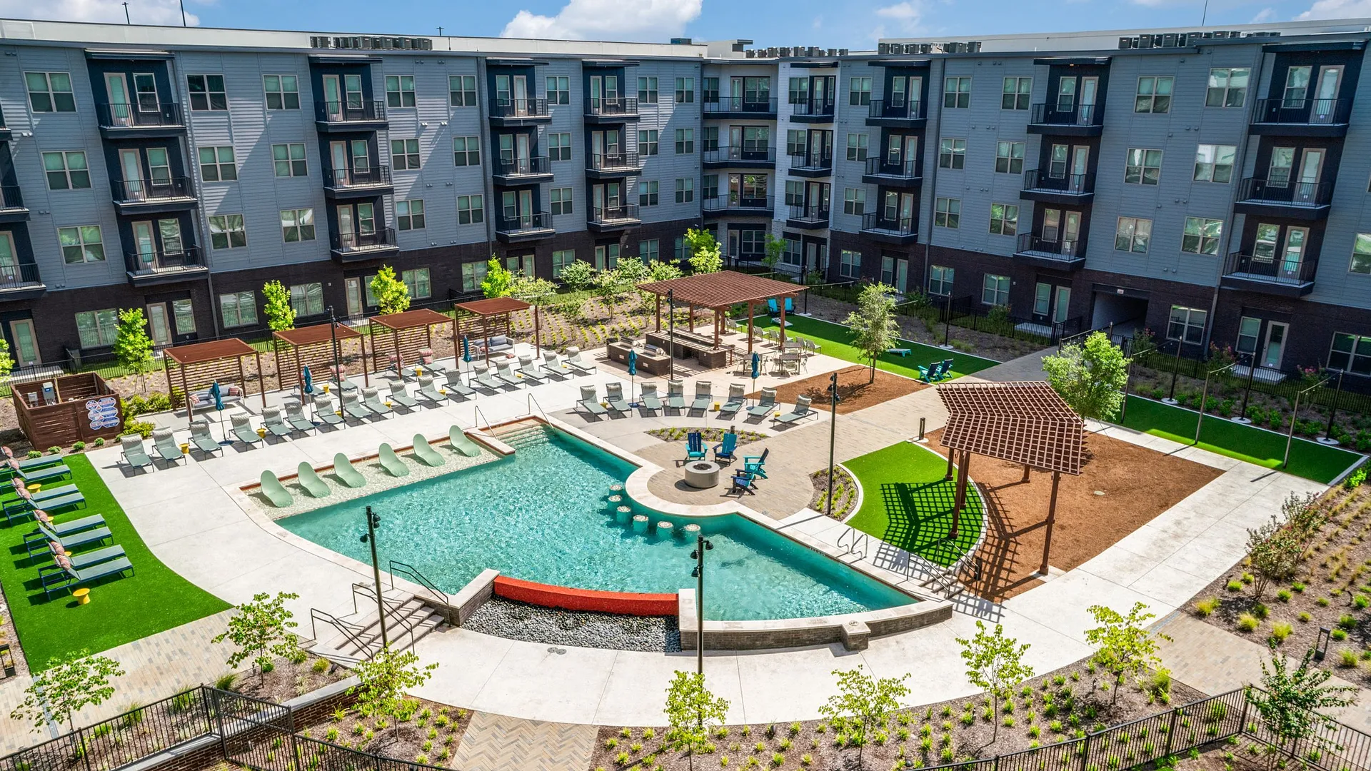 Aerial view of a modern apartment complex with a pool and amenities.
