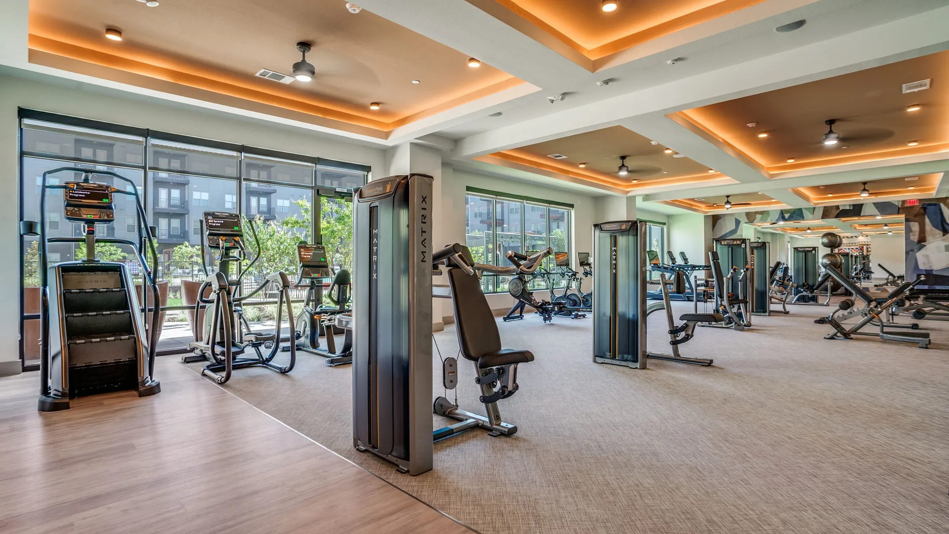 A modern gym featuring exercise equipment and large windows for natural light.