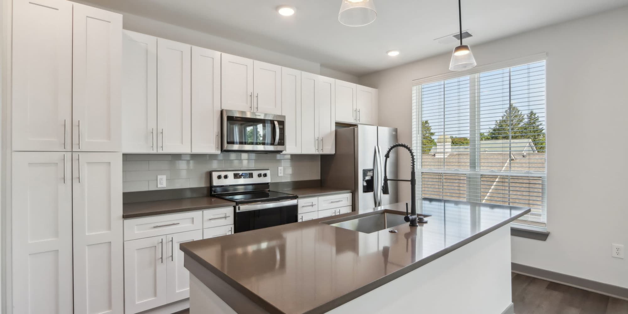Modern kitchen with stainless appliances at at The Apartments at 1st on Main in Carmel, IN