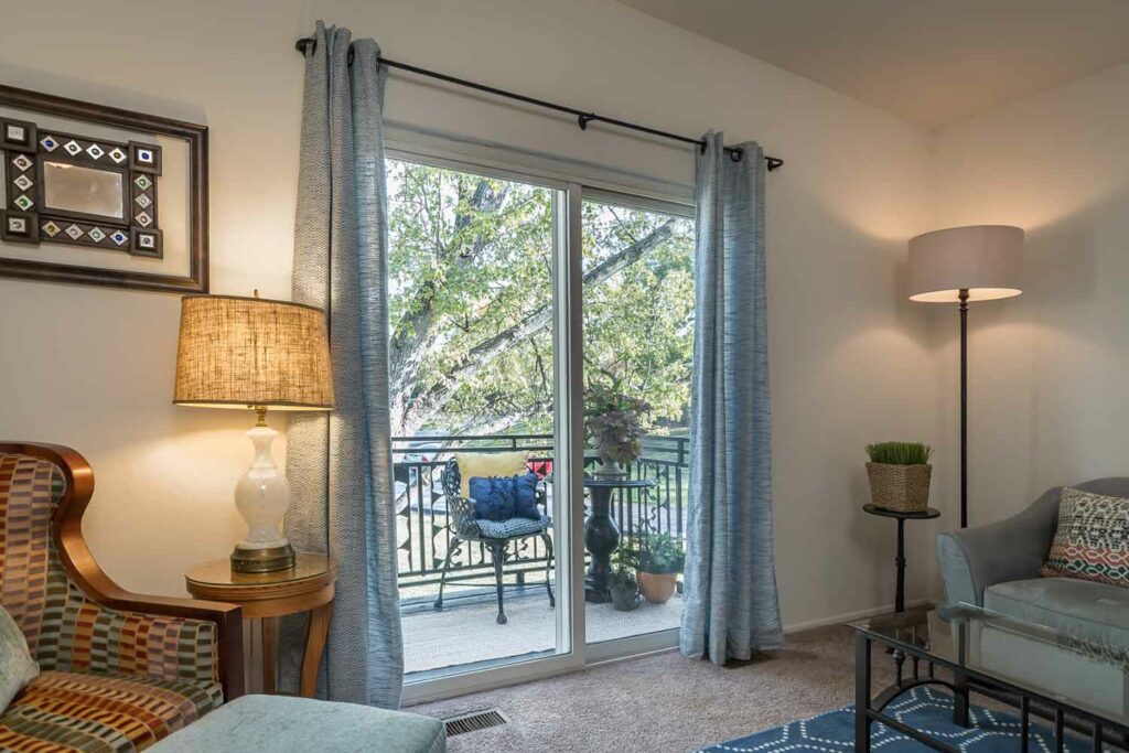 Living room with sliding glass door to furnished balcony at Courtland Ridge Apartments, St Charles, MO.