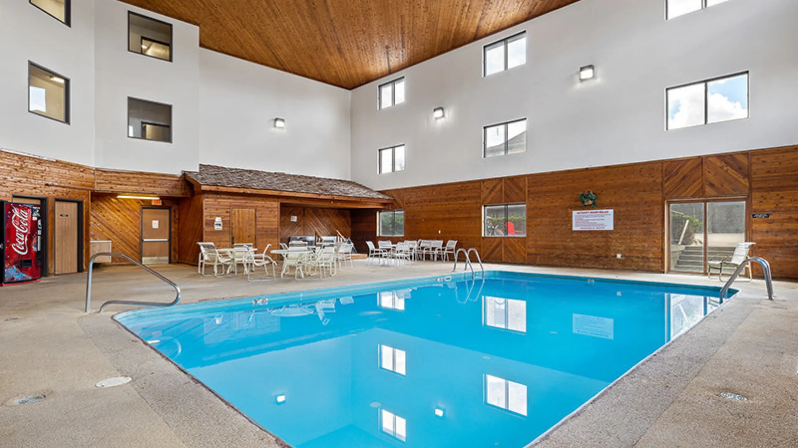 Elegant indoor swimming pool with wooden accents and ample seating, perfect for relaxation and hosting guests.