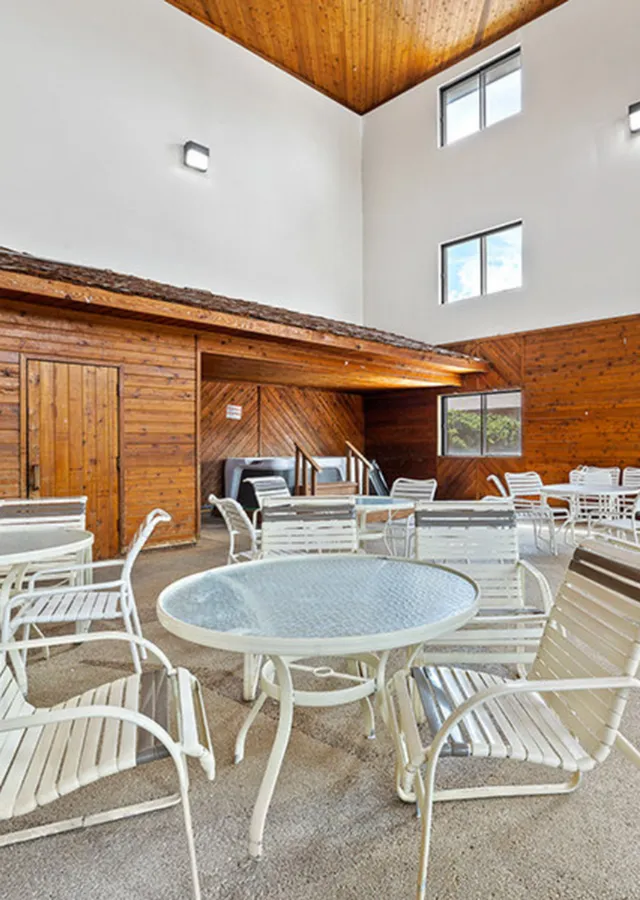 Charming indoor seating area with elegant white furniture, surrounded by warm wooden paneling and natural light.