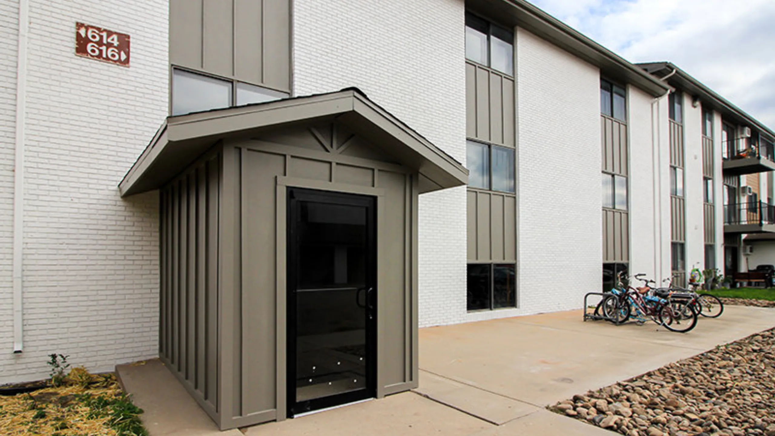 Charming modern apartment exterior with sleek white brick facade, secure entrance, and convenient bicycle parking.