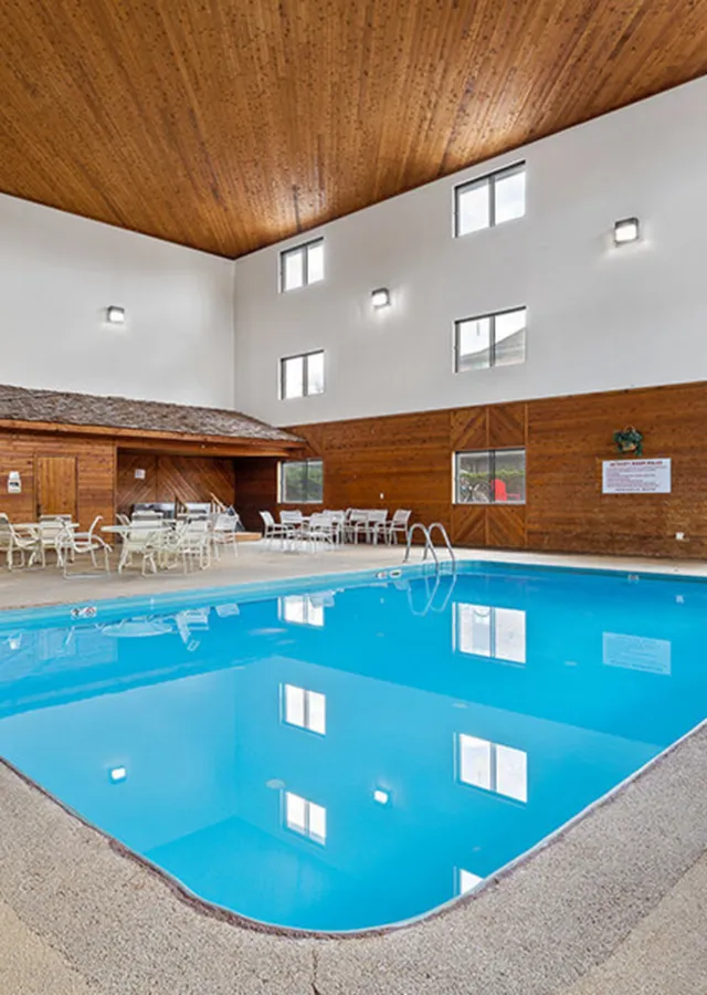 Inviting indoor swimming pool area with modern wooden accents and ample seating, perfect for relaxation and social gatherings.