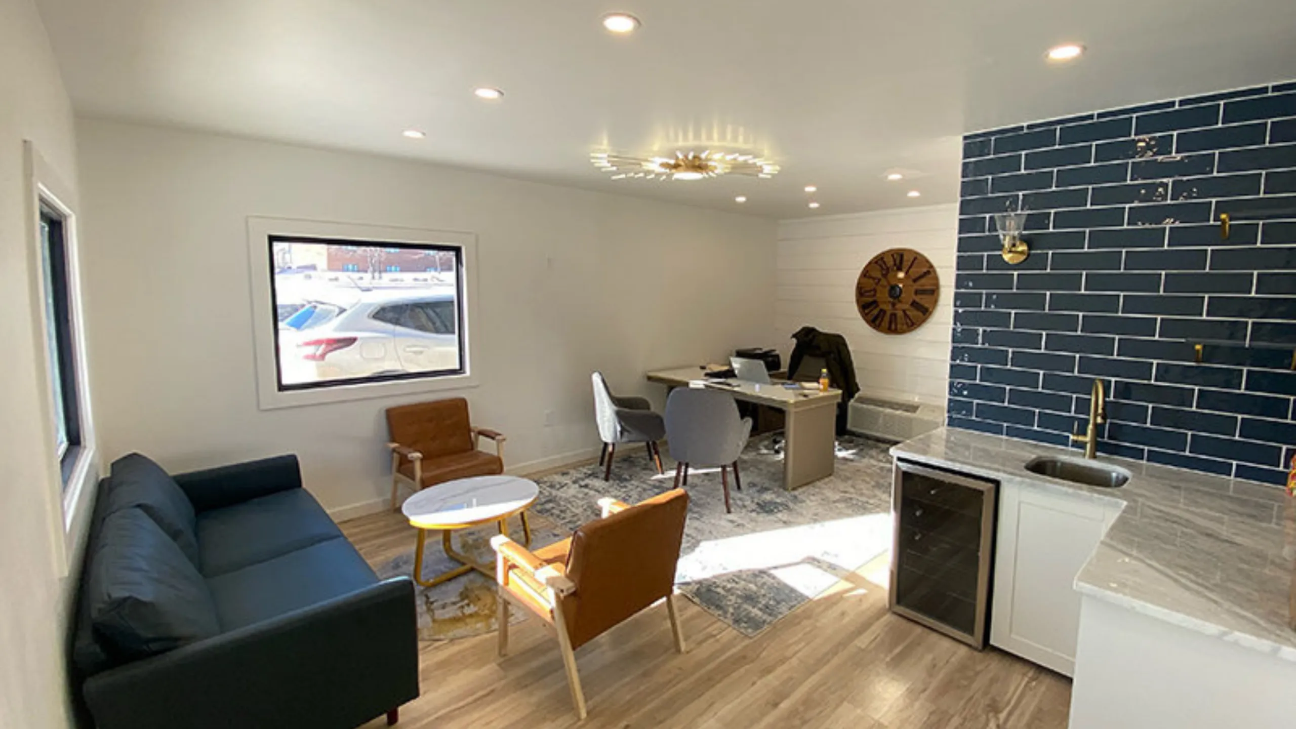 Modern open-concept living area with stylish blue accent wall, cozy seating, and a sleek kitchenette perfect for entertaining.