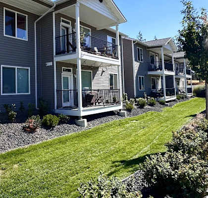 A row of modern apartment buildings with balconies and landscaped gardens.