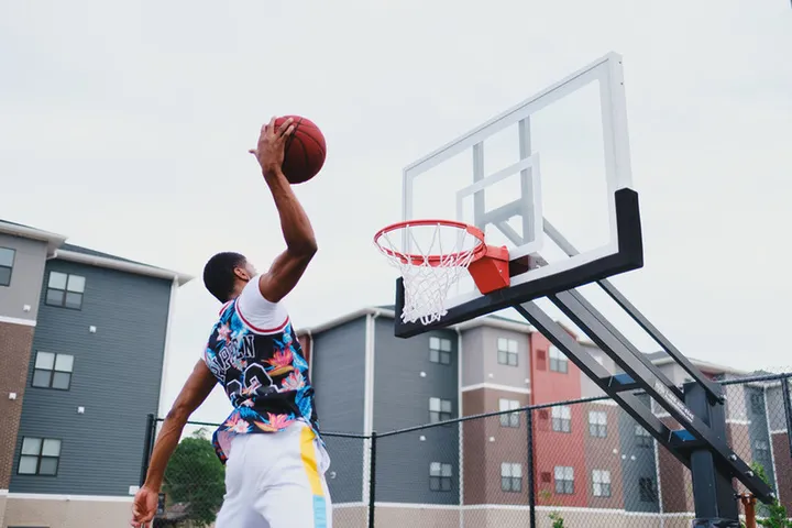 Energetic basketball game on a modern court with stylish apartment complex in the background.