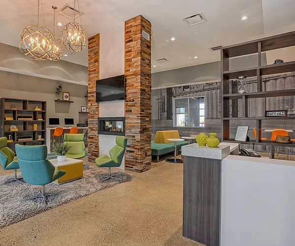 Vibrant apartment complex featuring modern buildings, a spacious outdoor area with colorful seating, and recreational facilities under a clear blue sky.