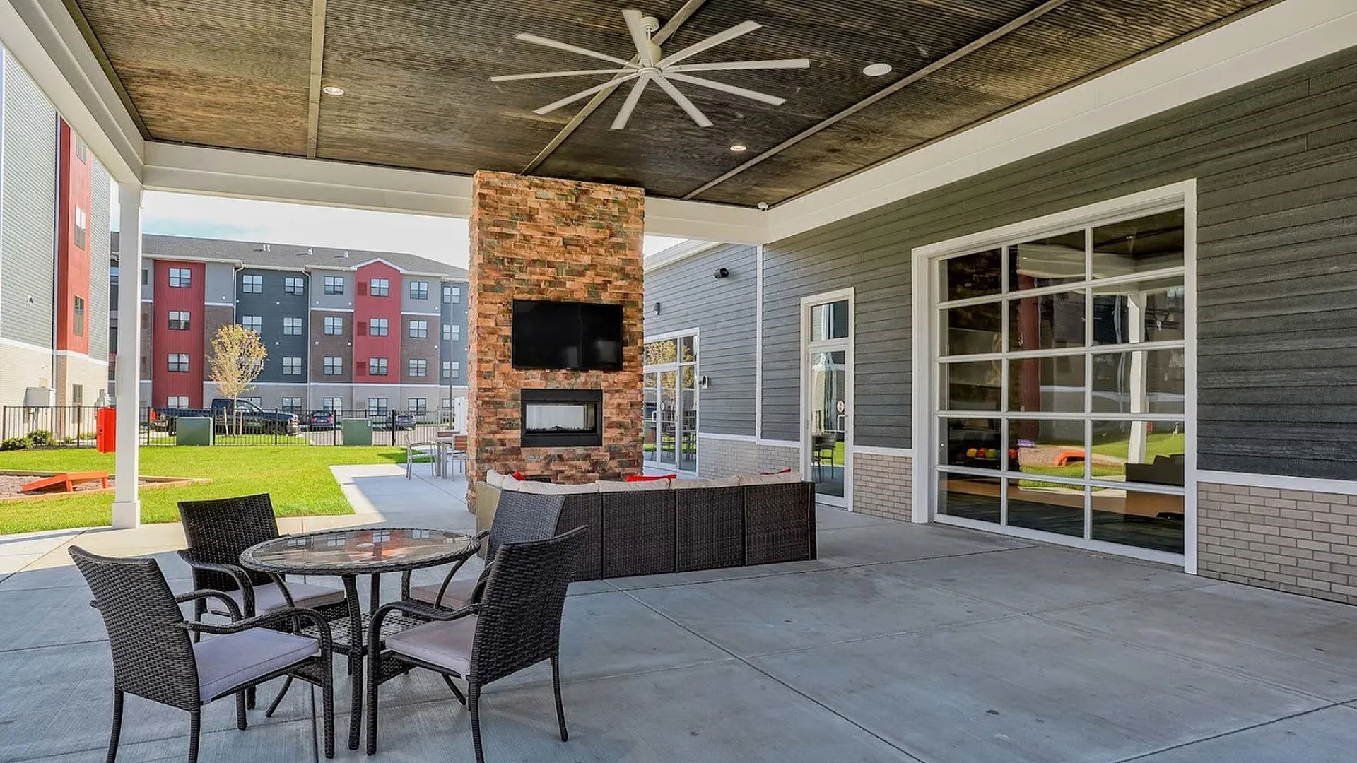 Chic outdoor patio featuring a cozy seating area, stylish dining table, modern fireplace, and built-in TV, perfect for relaxation and entertainment.