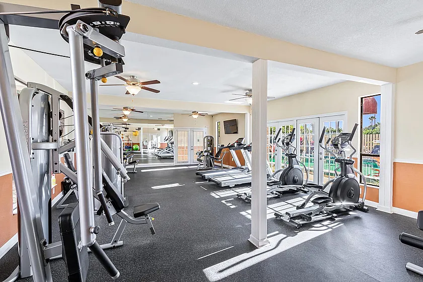 Spacious and bright fitness center featuring modern gym equipment with large windows and mirrored walls for an invigorating workout experience.