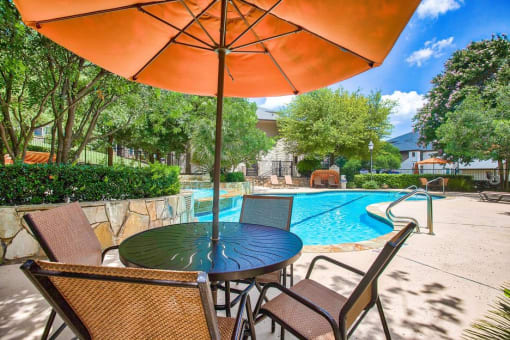 Mission oaks pool surrounded by trees and beach chairs and umbrella and club house