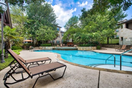 Mission oaks pool surrounded by trees and beach chairs and club house