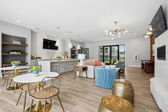 An interior view of a residential study lounge with a table, lounge chairs, and a lounge couch at The One at Columbia apartments in Columbia, SC