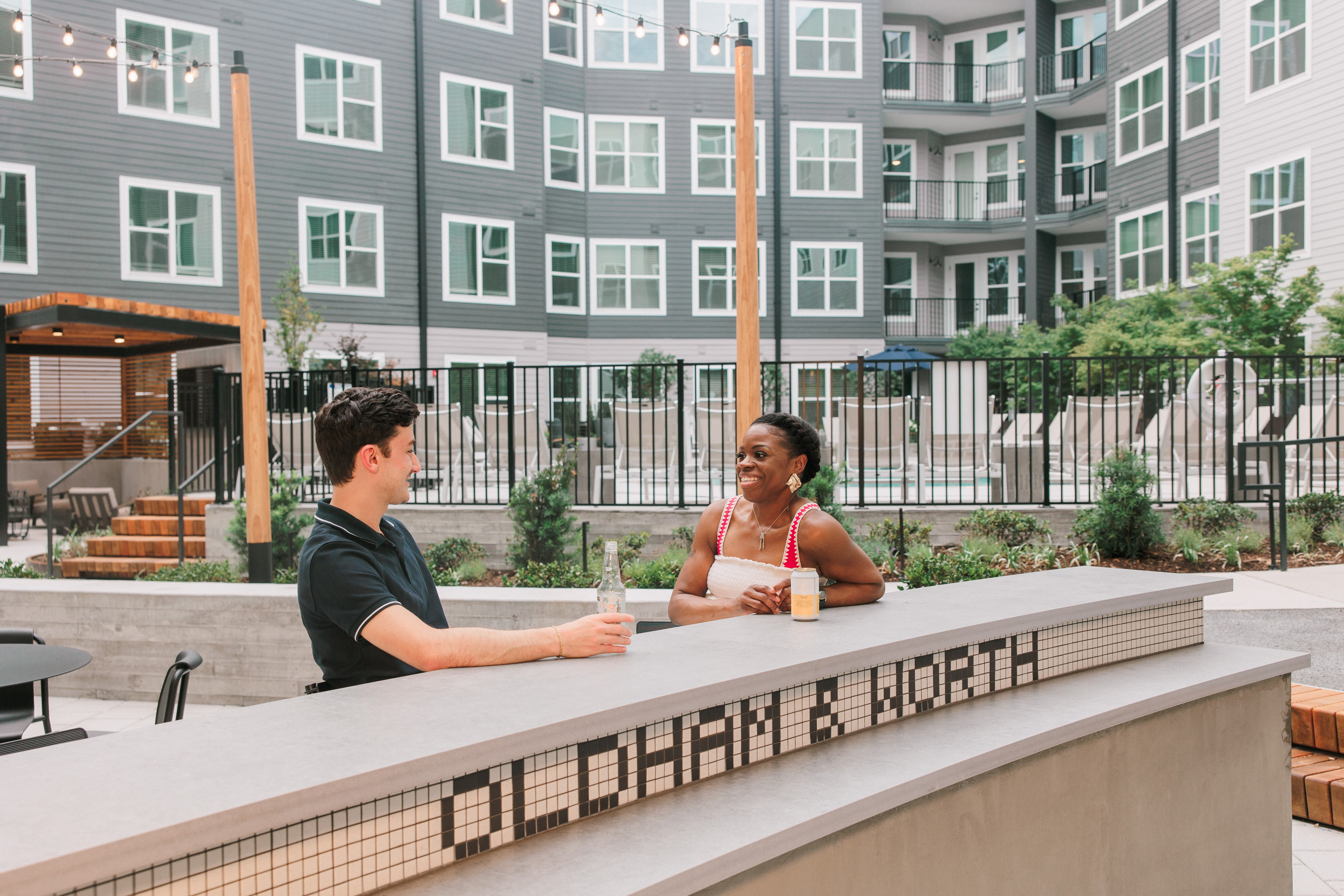 Residents chatting at outdoor bar with courtyard views at Oldham & Worth in Raleigh, NC