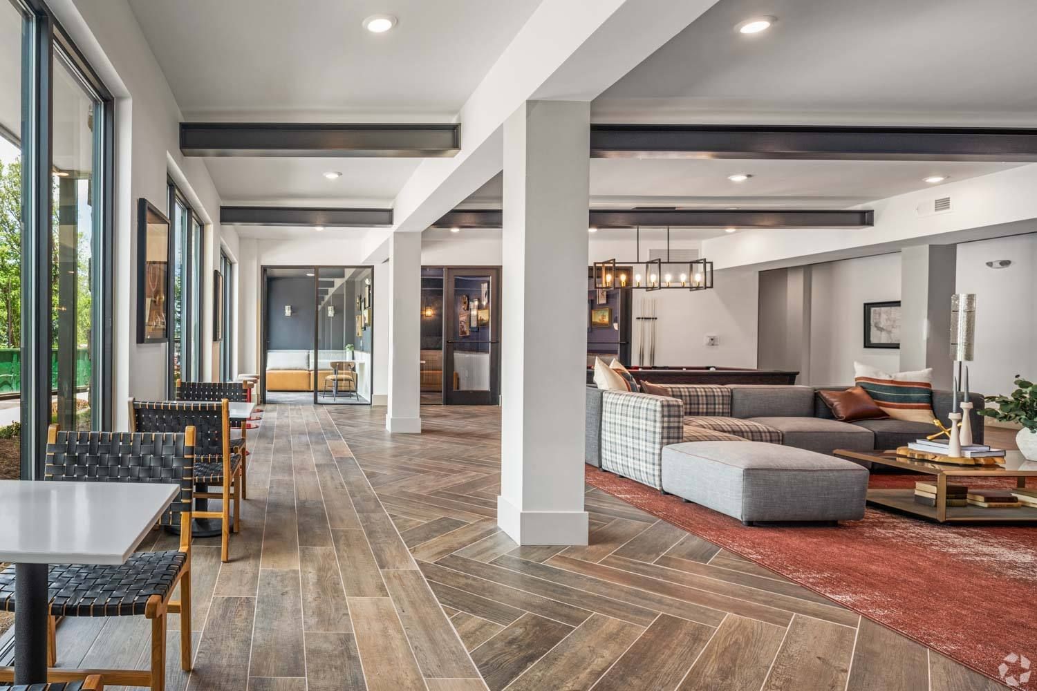 A room with a couch , chairs , tables and a pool table.