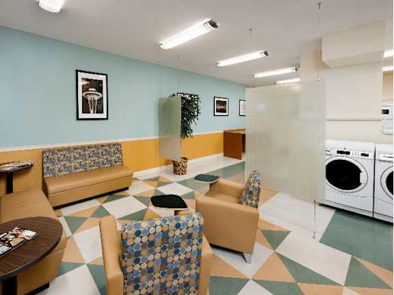 A laundry room with a washer and dryer and a couch at Skye Apartments, Seattle, 98121