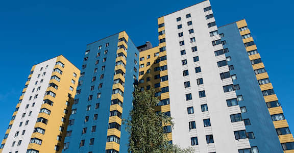 A tall building with a blue and yellow facade stands against a clear sky at Skye at Belltown Apartments, Washington 98121
