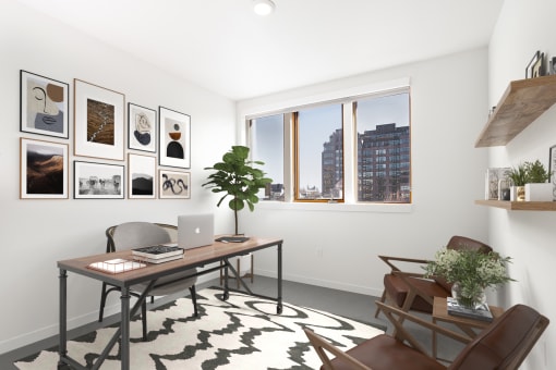 Home office with a desk and a window and a wall of framed photos