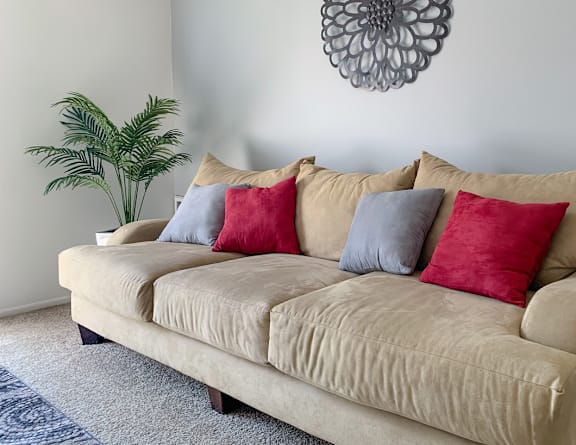 A beige couch with four pillows in red, blue, and grey  at The Lodge Apartments, Indianapolis, IN, 46205.