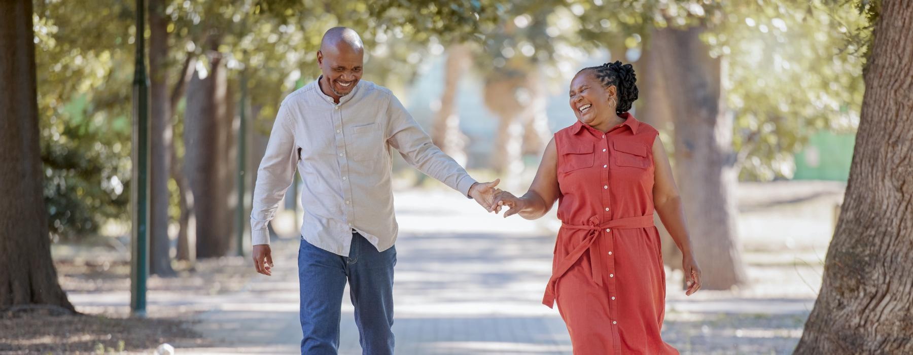 a man and woman walk through park, holding hands