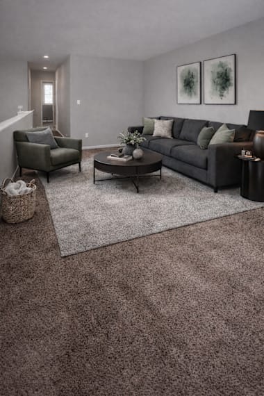 A living room with a grey couch, a coffee table, and two chairs.