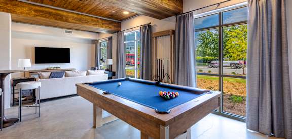 A pool table in a room with a wooden ceiling and a television.