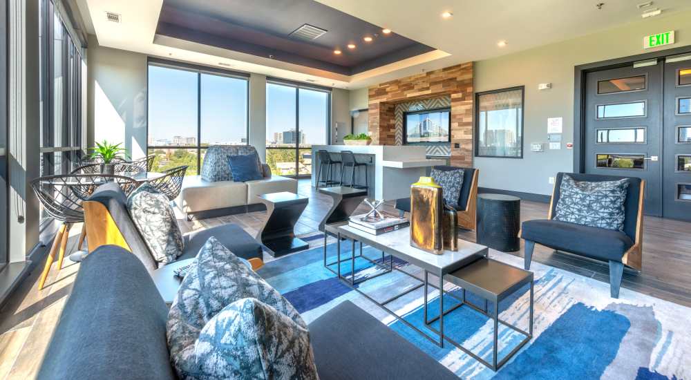 Resident lounge with a large seat in middle of room and multiple black chairs an tables with TVs and an island area at Hall Street Flats in Dallas, Texas