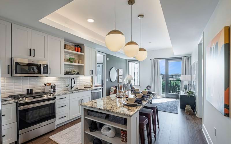 Spacious and well lit kitchen with wood floors and granite counters