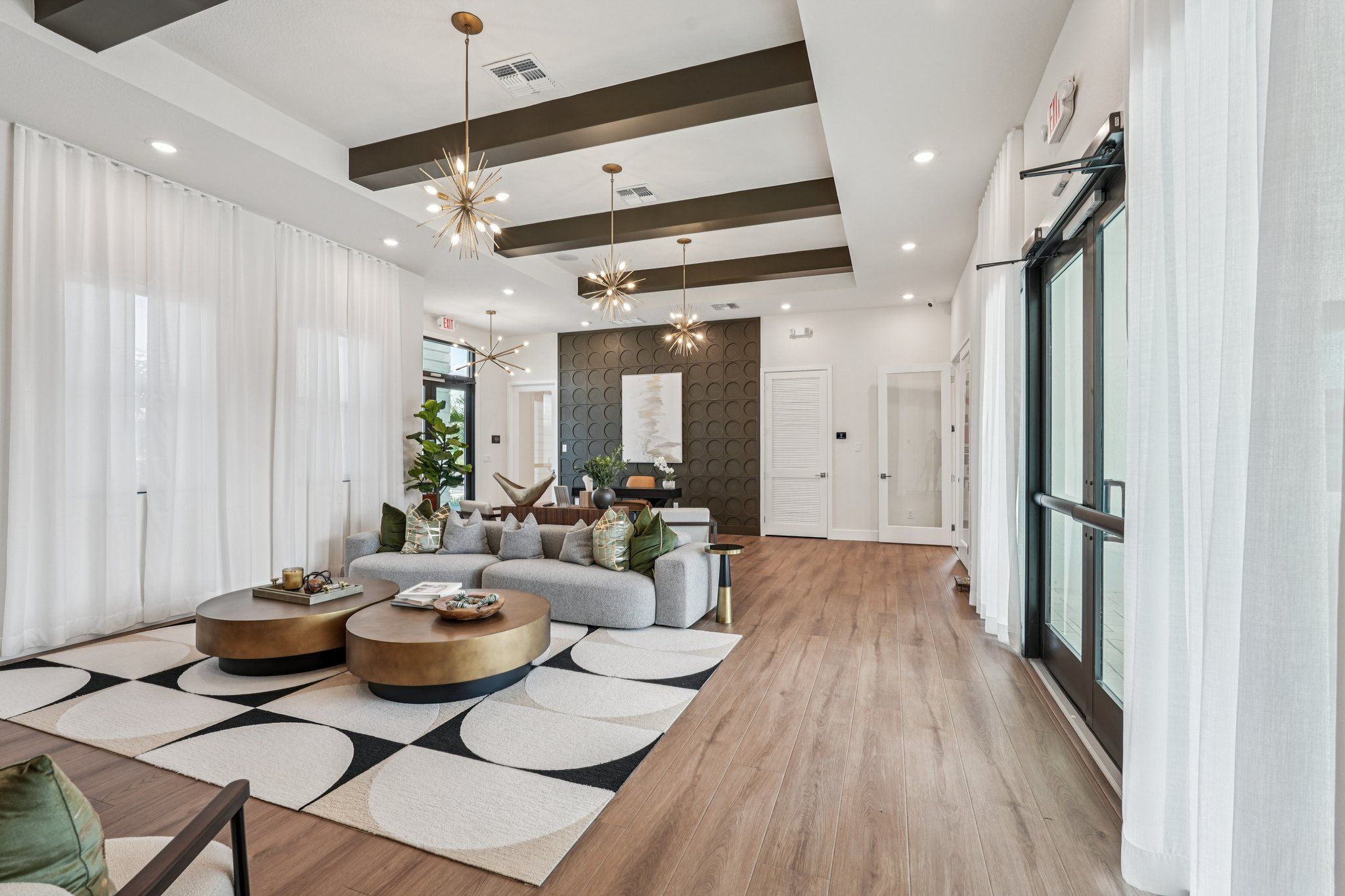 A modern, stylish lounge area with large windows, comfortable seating, and decorative light fixtures.